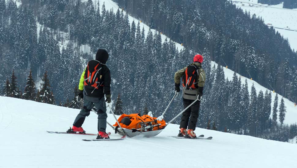 Injured skier being taken down mountain by rescue team