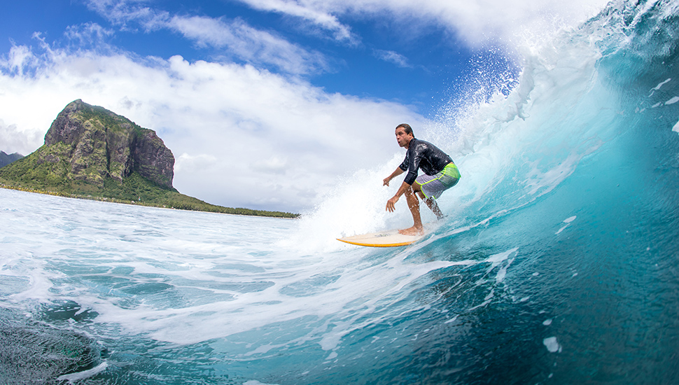 Surfing on big waves against the backdrop of picturesque mountains and beautiful clouds