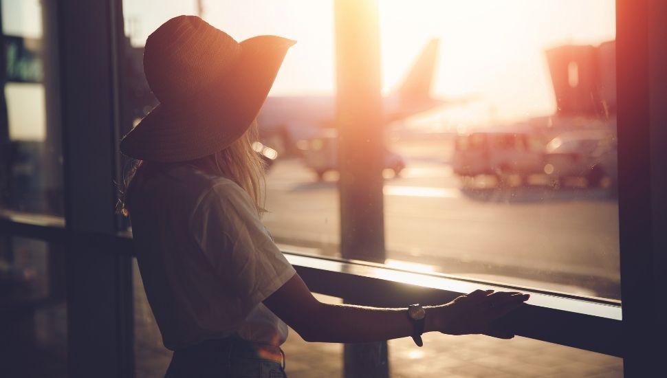 Woman looking out of window at airport at plane