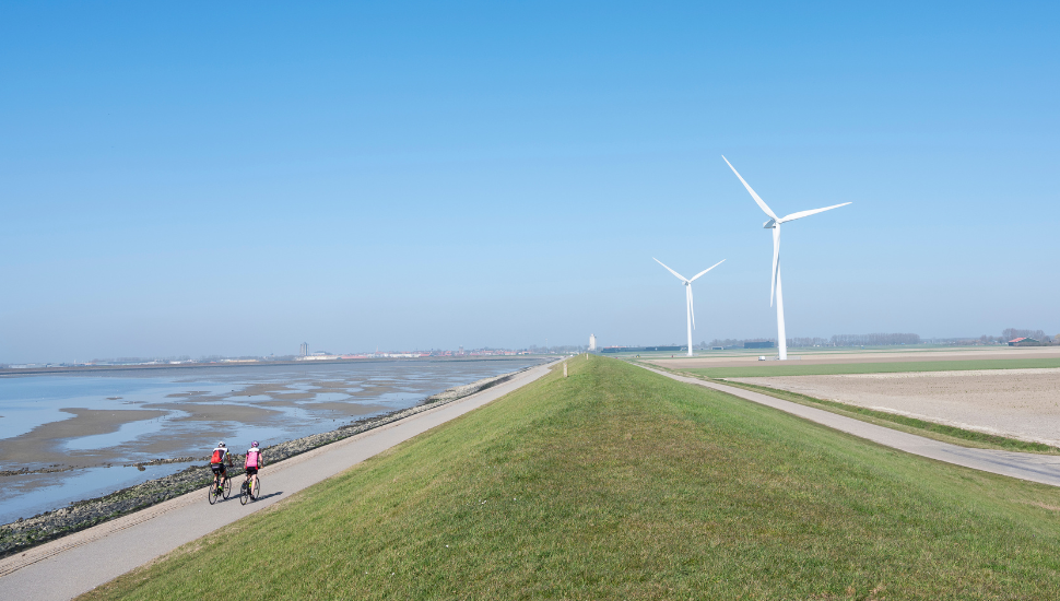 People on bicycles near wind turbines in rural landscape of Schouwen Duiveland