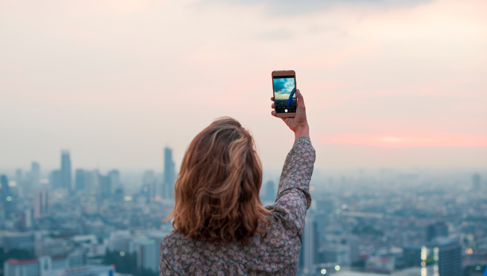 Solo female traveller taking a photo at sunset