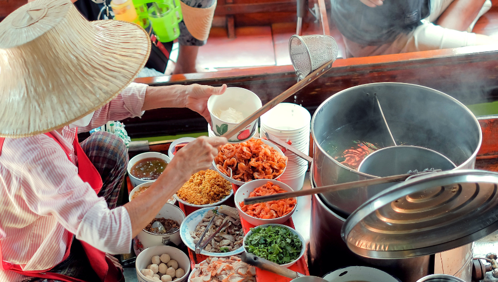 Thai lady preparing noodles on boat in the floating market