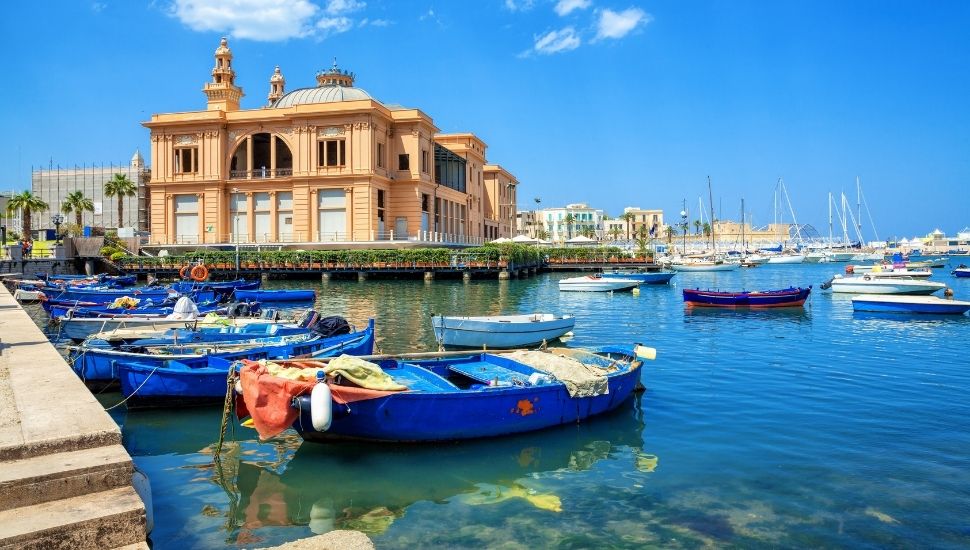 Margherita Theater and fishing row boat in old harbor of Bari, Italy