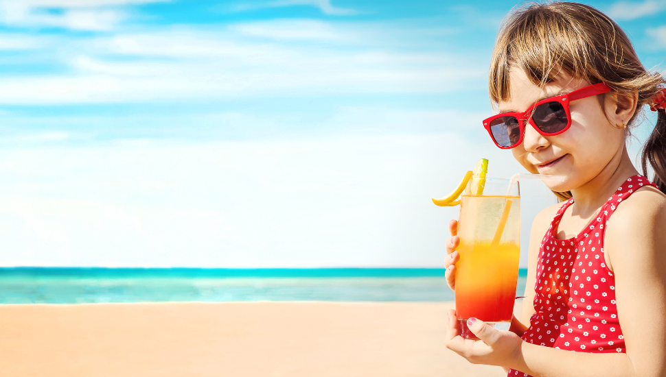 Young girl enjoying drink on beach