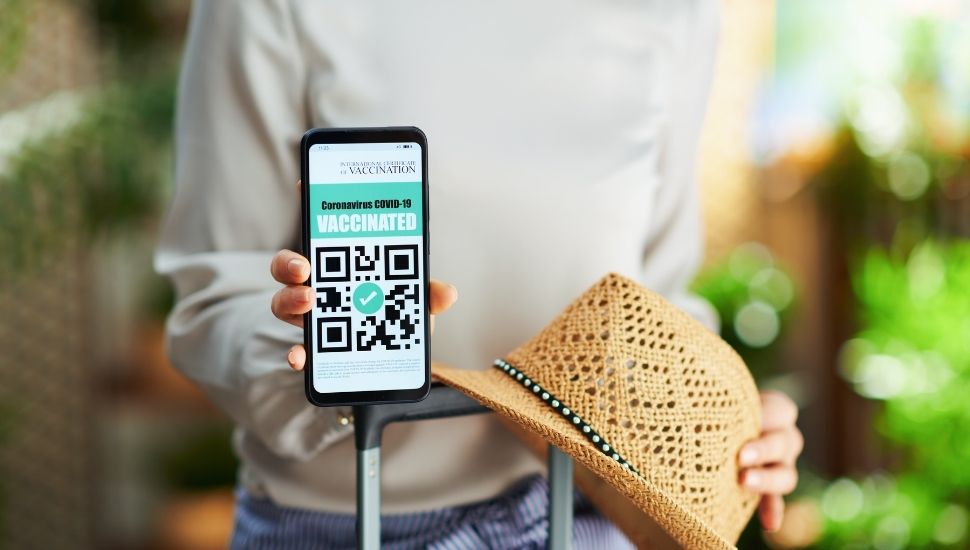 Woman holding phone displaying Covid-129 vaccine passport status