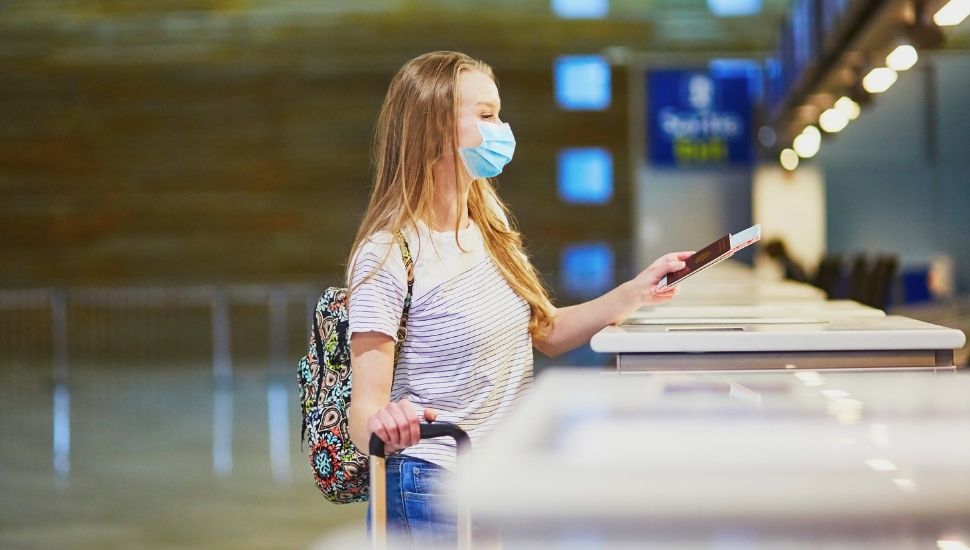 Girl wearing facemask at airport check-in desk